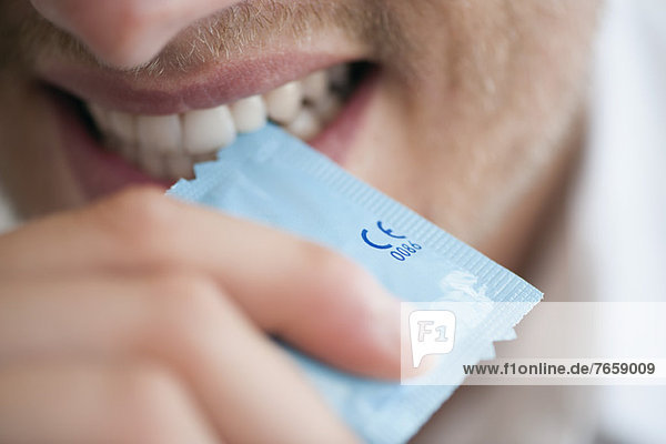 Mann reißt Kondomhülle mit den Zähnen auf