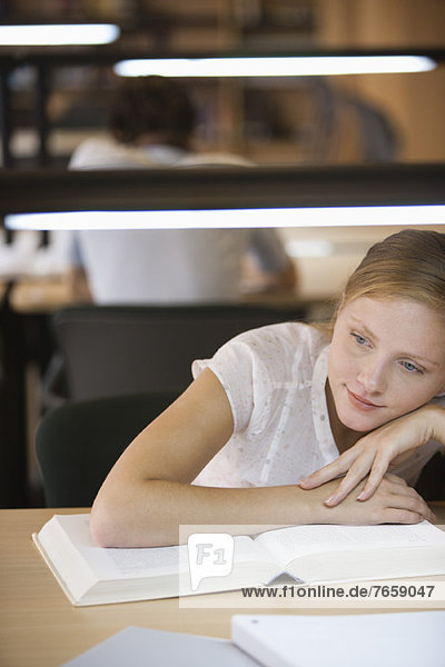 Junge Frau träumt während des Studiums