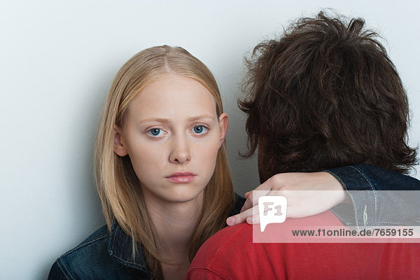 Young woman embracing man  looking at camera with serious expression