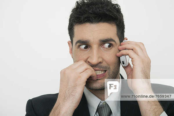 Mid-adult businessman talking on cell phone with anxious expression