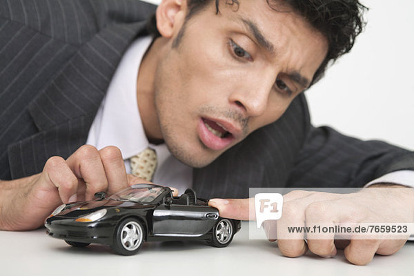 Mid-adult businessman looking at toy car