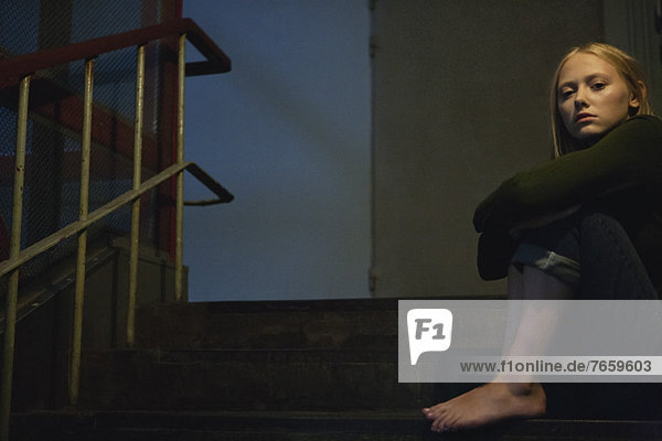 Young woman sitting on stairs  hugging knees