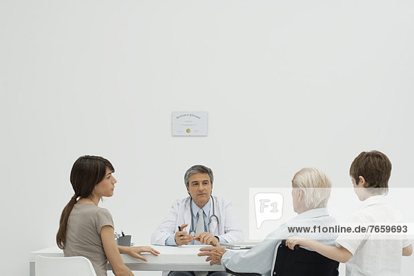 Arzt im Gespräch mit dem älteren Patienten und seiner Familie