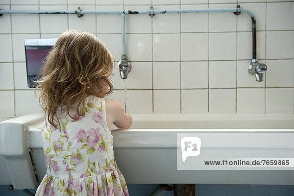 Little girl washing hands in bathroom  rear view