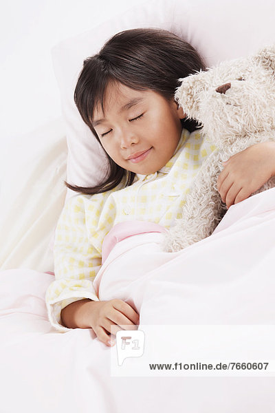 Girl sleeping in bed with a teddy bear