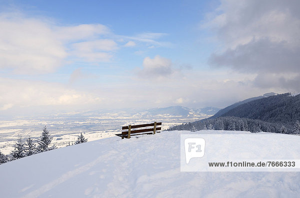 Sitzbank auf Berggipfel  Ausblick ins winterlich verschneite Rosenheimer Becken und Chiemgauer Alpen