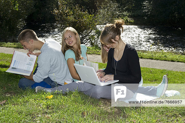 Students with a laptop and books on a meadow  Freiburg im Breisgau  Baden-Wuerttemberg  Germany  Europe