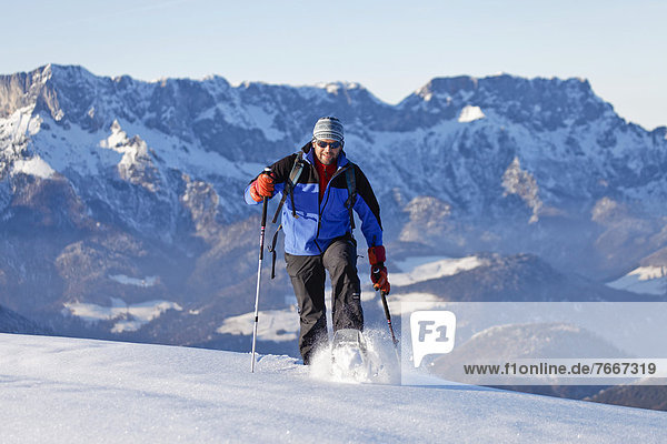 Man snowshoeing  snowshoe tour in Berchtesgadener Land  Unterberg mountain and Hochthron mountain at the back  Berchtesgadener Land  Bavaria  Germany  Europe