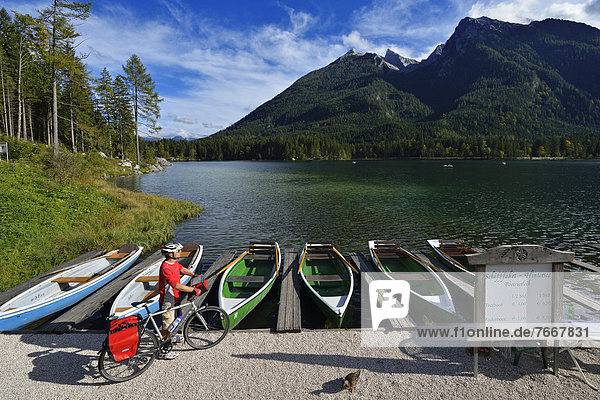 Radfahrer steht vor Booten am Hintersee  Ramsau  Berchtesgaden  Oberbayern  Bayern  Deutschland  Europa