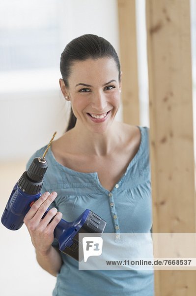 Portrait of woman using hand drill