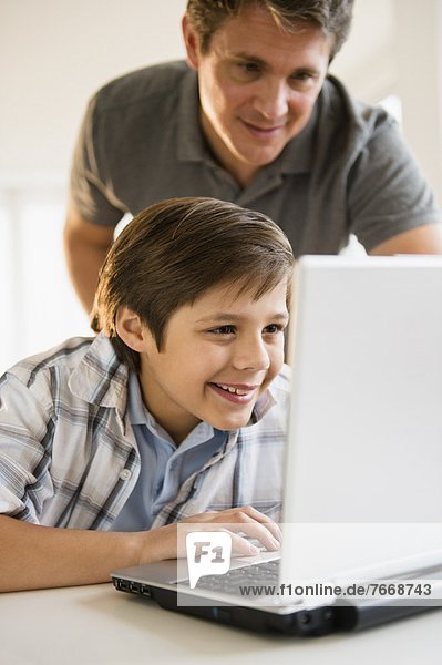 Father and son (8-9) using laptop
