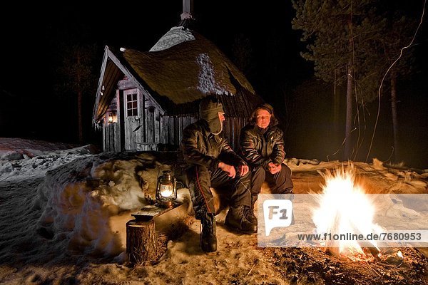 Europe  Sweden  Skelleftea  svansele wilderness camp  people resting at fireplace                                                                                                                       
