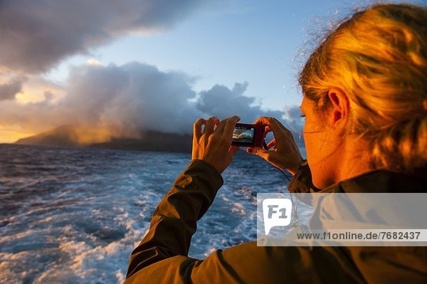 Tourist photographing Tau Island at sunrise  Manua Island group  American Samoa  South Pacific  Pacific