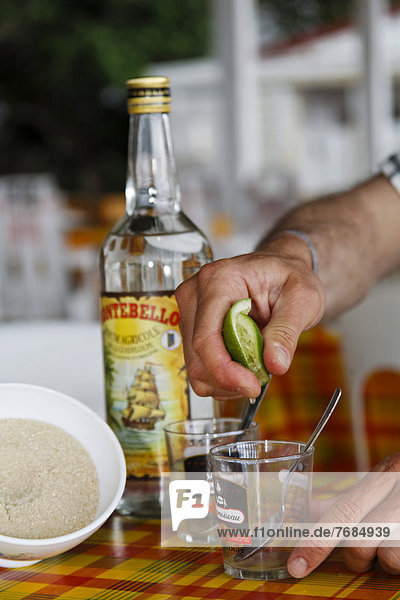Ti-Punch  Zubereitung des Nationalgetränks mit Limone  Rohrzucker und Rum  Guadeloupe  Karibik  Kleine Antillen