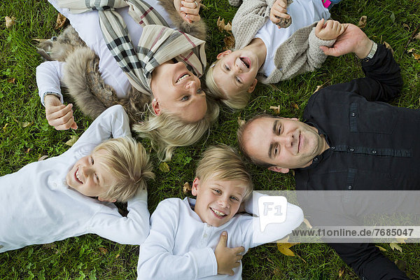 Familie mit drei Kindern liegt im Gras