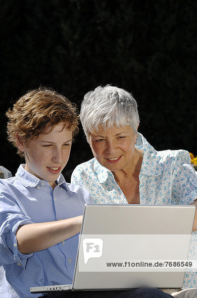 Grandson is showing his grandmother something on a laptop computer