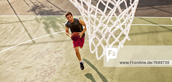 Mann spielt Basketball auf dem Platz