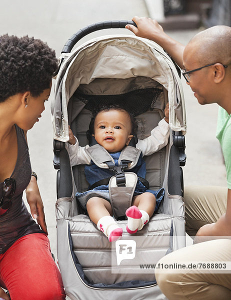 Eltern mit Baby im Kinderwagen auf der Stadtstraße