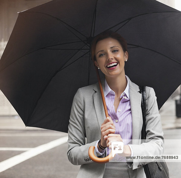 Geschäftsfrau mit Regenschirm auf der Stadtstraße