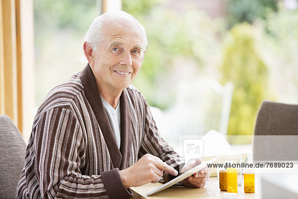 Älterer Mann mit Tablet-Computer am Tisch