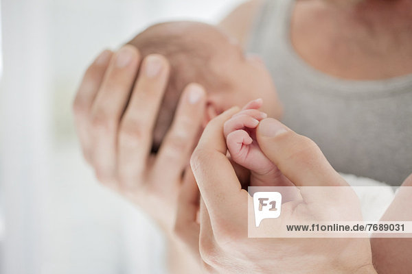 Mutter wiegt die Hand des Neugeborenen