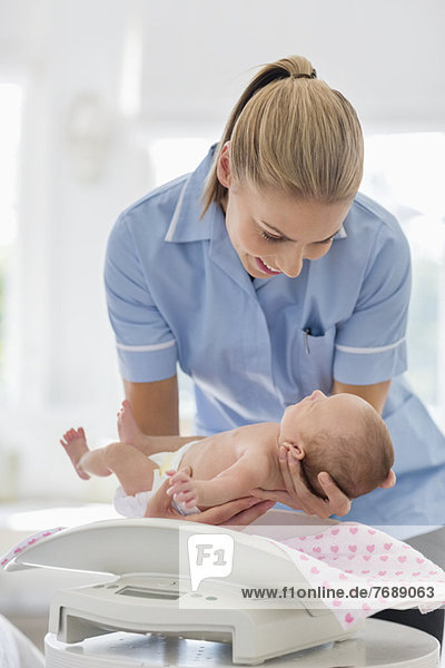 Krankenschwester beim Wiegen von Neugeborenen