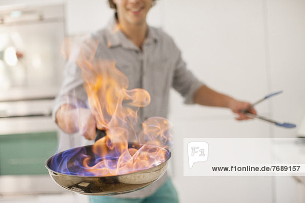 Man cooking with fire in kitchen