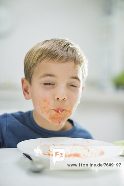 Boy slurping spaghetti at table