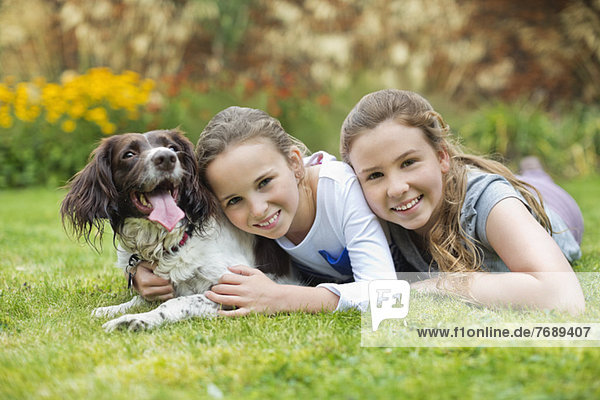 Lächelnde Mädchen entspannen mit Hund auf dem Rasen