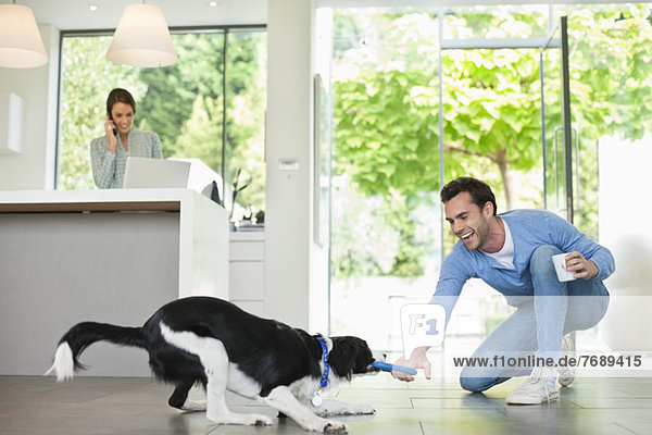 Man playing with dog in kitchen