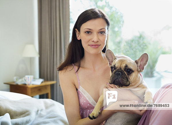 Woman petting dog in bed