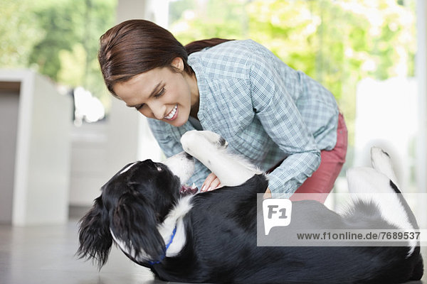 Lächelnde Frau spielt mit Hund