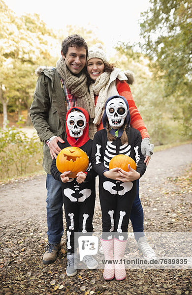 Eltern lächeln mit Kindern in Skelettkostümen