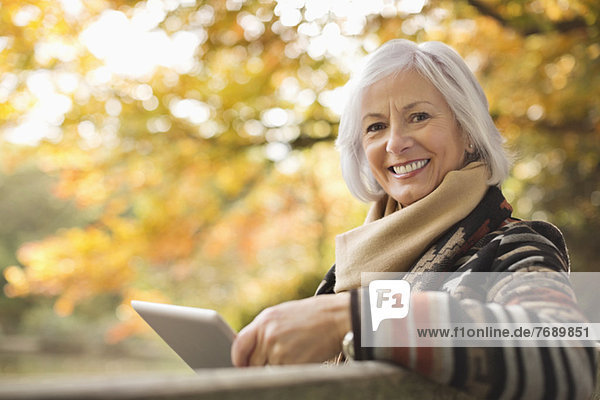 Older woman using tablet computer outdoors