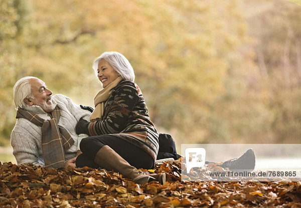 Older couple sitting in autumn leaves