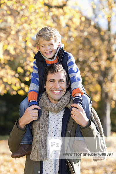 Man carrying son on shoulders in park