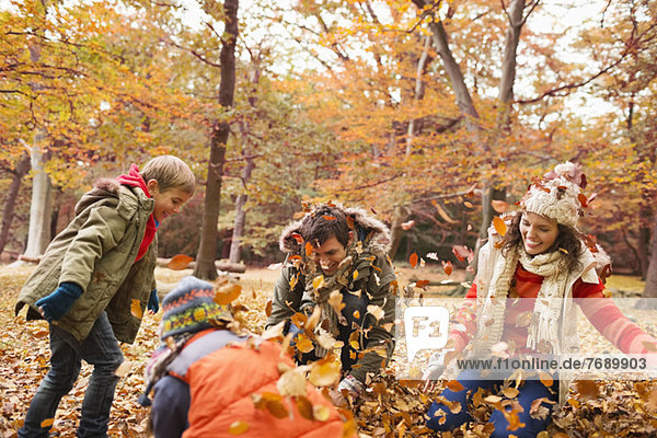Family playing in autumn leaves in park