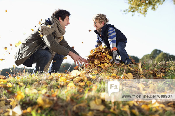Vater und Sohn spielen im Herbstlaub
