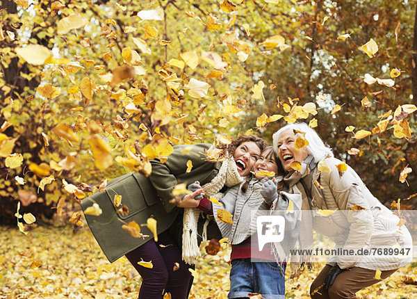 Three generations of women playing in autumn leaves