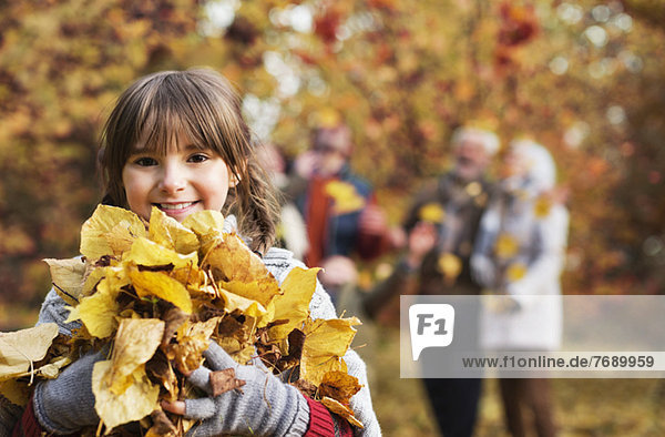 Mädchen spielt mit Herbstblättern im Park