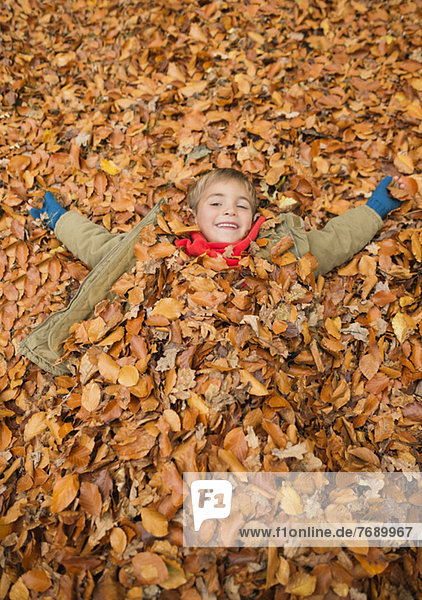 Boy laying in autumn leaves