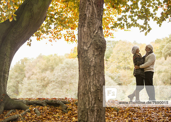 Older couple hugging in park