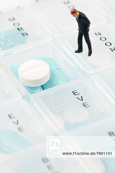 Businessman miniature figurine on pill box