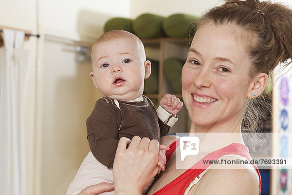 Smiling mother holding baby in yoga studio