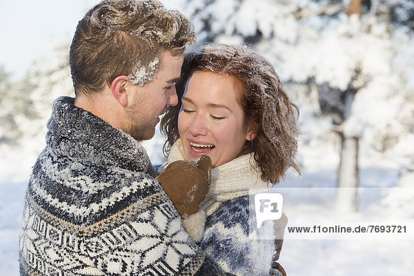 Caucasian couple hugging in snow