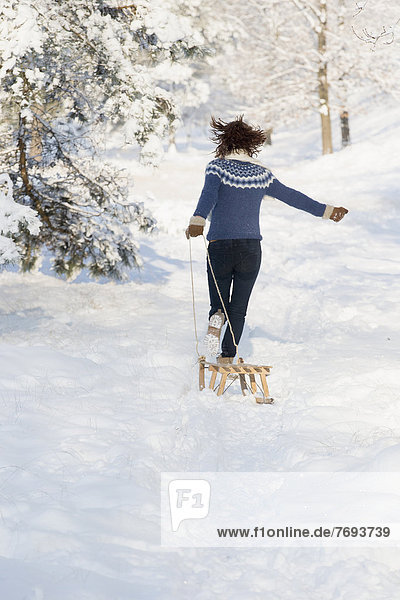 Caucasian woman pulling sled in snow