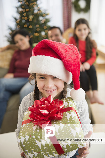Girl in Santa hat holding Christmas present