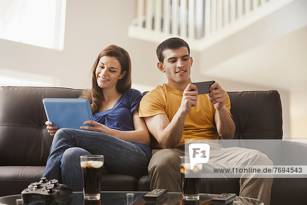 Couple relaxing with technology on sofa