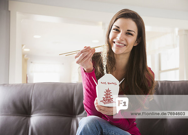 Caucasian woman eating Chinese food on sofa