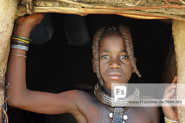 Himba girl with two braids and jewellery portrait Himba hut Himba village